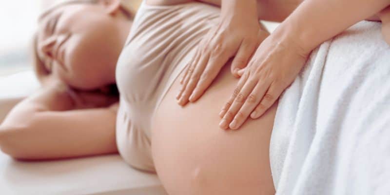 lano detalle de manos realizando masaje de drenaje linfático en la barriga de una mujer embarazada en Madrid